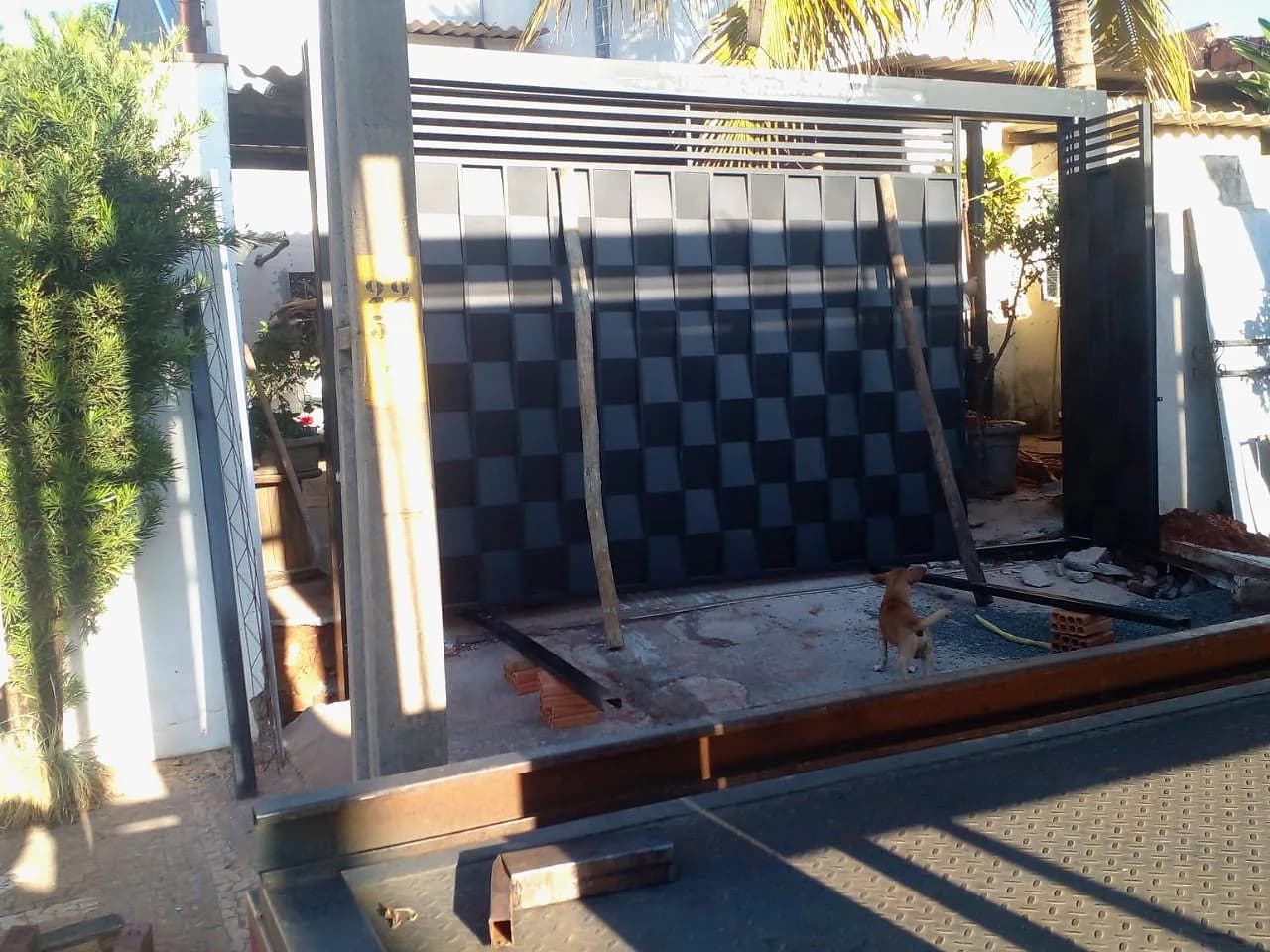 Portão sendo posicionado na obra, visto da carroceria do caminhão