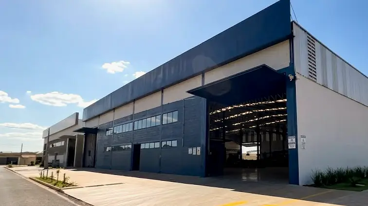 Fachada do galpão da fábrica da Portões Rio Preto, com o portão de carga aberto e o pátio de concreto em frente
