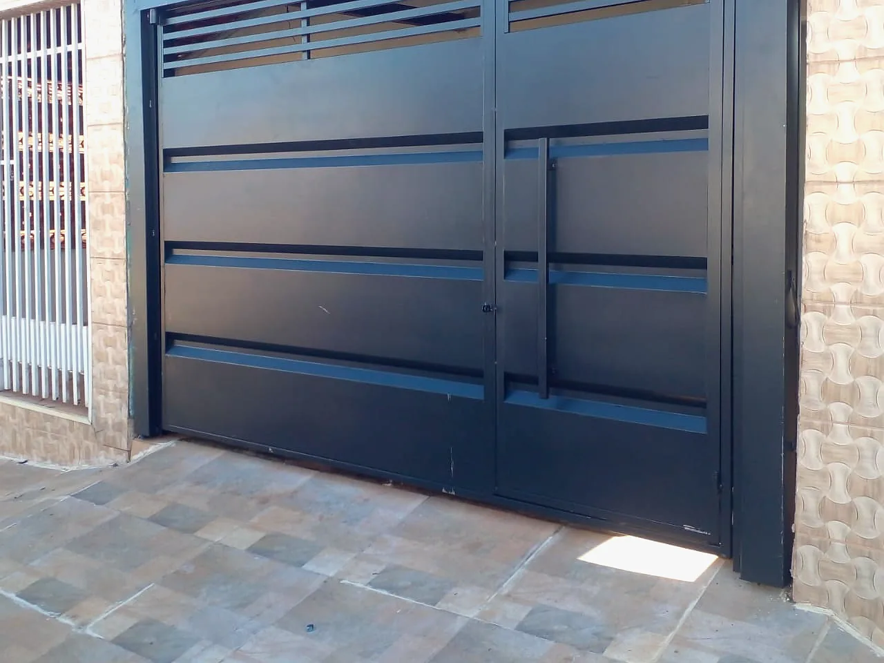 Portão basculante com frisos horizontais em garagem residencial